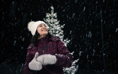 woman outdoors enjoying a snowy Christmas